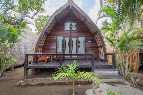 a small wooden cabin with a porch and a balcony at Omah Gili Hotel in Gili Air