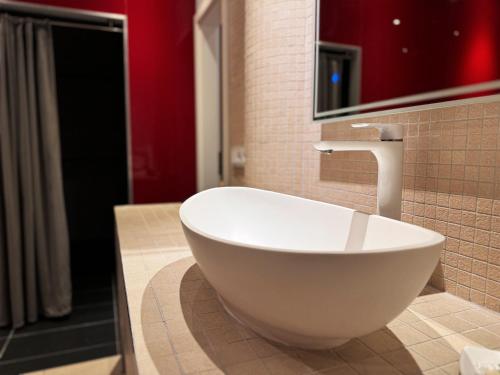 a bathroom with a white bowl sink and red walls at Grimm's Berlin Mitte in Berlin