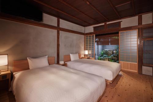 two beds in a room with a window and two lamps at HOTEL CULTIA DAZAIFU in Dazaifu