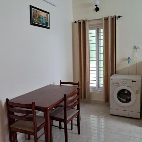 a dining room with a table and a washing machine at Yazh Vedha Homes in Chennai