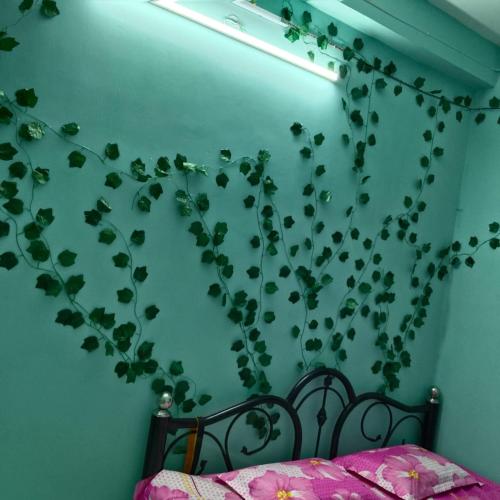 a bedroom with a green wall with a plant on it at Piyari home stay in Kolkata