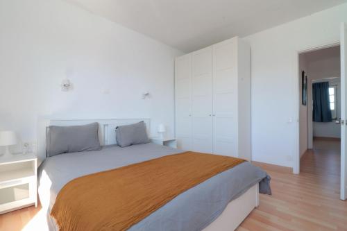 una camera da letto con un grande letto, pareti bianche e pavimenti in legno di Apartamento recién reformado en la playa a Costa Teguise