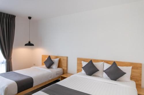 a hotel room with two beds and a window at Ananzitra Hotel in Kanchanaburi