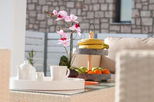 einen Tisch mit einem Tablett mit Obst und einem Teller mit Essen in der Unterkunft Francis & Gregorys Luxury Villas in Afandou