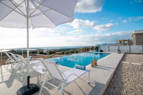 a patio with chairs and an umbrella and a pool at Francis & Gregorys Luxury Villas in Afantou