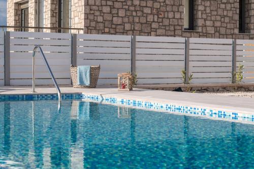 a swimming pool with blue water in front of a fence at Francis & Gregorys Luxury Villas in Afantou