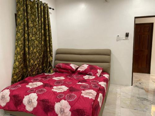 a bedroom with a red bed with flowers on it at Sepang Putra Bagan Lalang Semi D House in Sungai Pelik