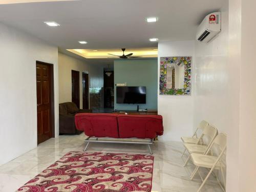 a living room with a red couch and a tv at Sepang Putra Bagan Lalang Semi D House in Sungai Pelik