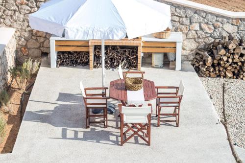 a patio with a table and chairs and an umbrella at Francis & Gregorys Luxury Villas in Afantou