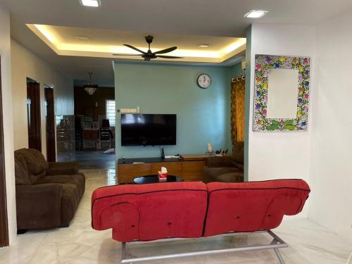 a living room with a red couch and a tv at Sepang Putra Bagan Lalang Semi D House in Sungai Pelik