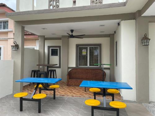 a patio with two blue tables and yellow stools at Sepang Putra Bagan Lalang Semi D House in Sungai Pelik