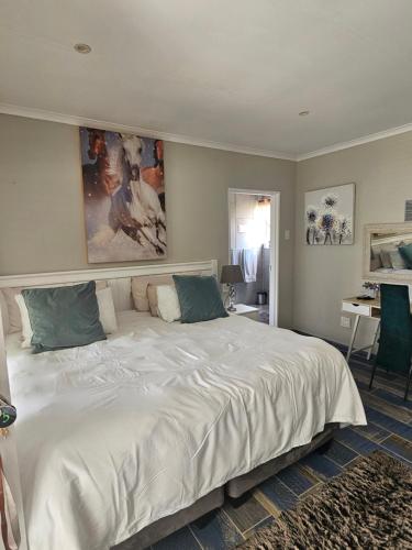 a large white bed in a room with a desk at The Armagh Guesthouse in Boksburg