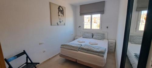 a small bedroom with a bed and two windows at Mazarron Beach apartment in Mazarrón