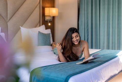 a woman laying on a bed reading a book at Shivsagar Resort & Spa in Mahabaleshwar