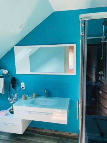 une salle de bain bleue avec un lavabo et un miroir dans l'établissement GITE des teilles, à Carlux