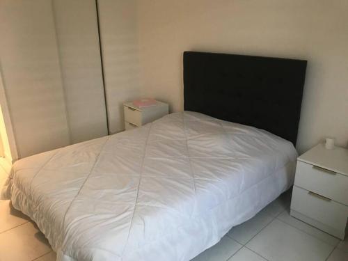 a bedroom with a white bed with a black headboard at Logement à Tassin avec piscine et garage in Tassin-la-Demi-Lune