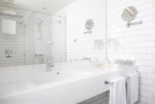 a white bathroom with a tub and a sink at Støtvig Hotel in Moss
