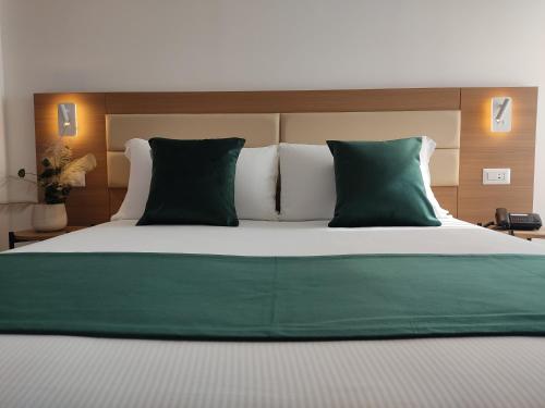 a bedroom with a large bed with green and white pillows at Massimi City Garden in Rome