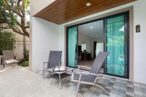 two chairs and a table on a patio at The Bell Airport Phuket Hotel - SHA Extra Plus in Nai Yang Beach