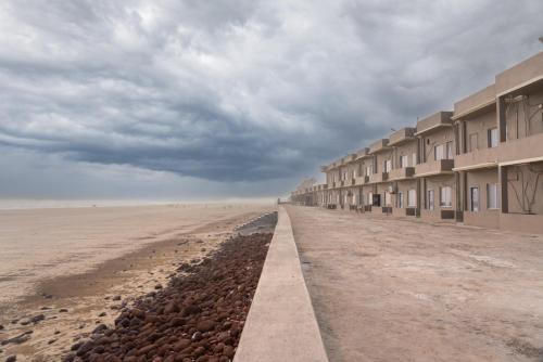 a row of buildings on the beach under a cloudy sky at Hotel Nilkantha in Mandarmoni