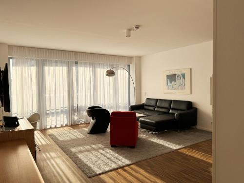 a living room with a black couch and a red chair at Grimm's Berlin Mitte in Berlin