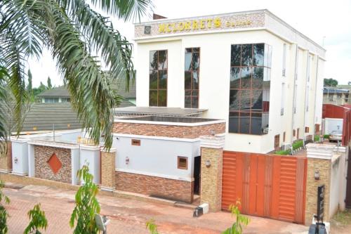 um edifício com uma vedação vermelha à sua frente em MCLORRETS SUITES em Enugu