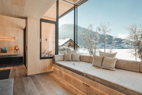 a living room with a couch and a large window at Alpenhotel Kitzbühel am Schwarzsee - 4 Sterne Superior in Kitzbühel