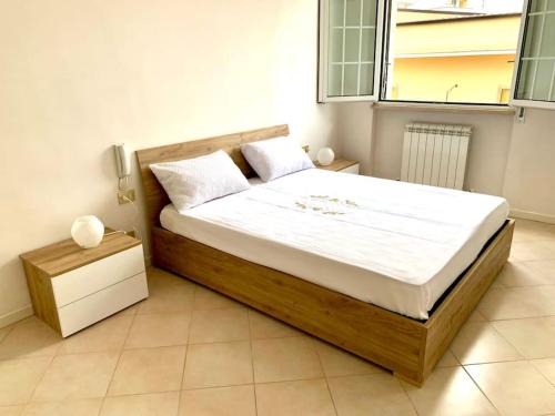 - une chambre dotée d'un grand lit avec des draps blancs et une fenêtre dans l'établissement G & G Appartamento nuovo, moderno e grazioso., à San Nicandro Garganico