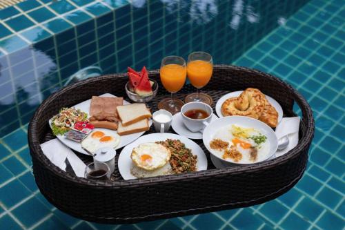 a tray of breakfast food on a table next to a pool at The Bell Airport Phuket Hotel - SHA Extra Plus in Nai Yang Beach