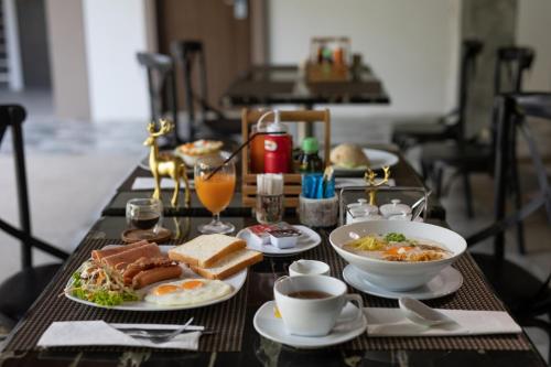 a table topped with plates of food and cups of coffee at The Bell Airport Phuket Hotel - SHA Extra Plus in Nai Yang Beach