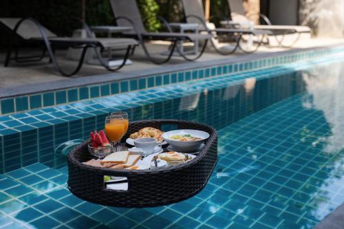 a tray of food and drinks next to a swimming pool at The Bell Airport Phuket Hotel - SHA Extra Plus in Nai Yang Beach