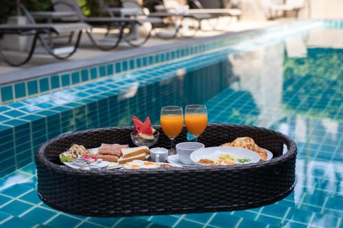 a tray of food and drinks on a table by a pool at The Bell Airport Phuket Hotel - SHA Extra Plus in Nai Yang Beach