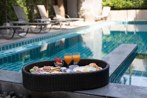 a tray of food and drinks next to a swimming pool at The Bell Airport Phuket Hotel - SHA Extra Plus in Nai Yang Beach