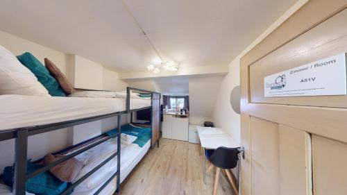 a small room with two bunk beds and a desk at Solution-Grischun - Zentrales Dachzimmer - Kaffee&Tee - Gemeinschaftsbad - Etagenbett -Dachterrasse in Chur