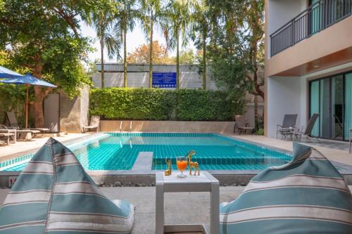 a swimming pool with two umbrellas in front of a building at The Bell Airport Phuket Hotel - SHA Extra Plus in Nai Yang Beach