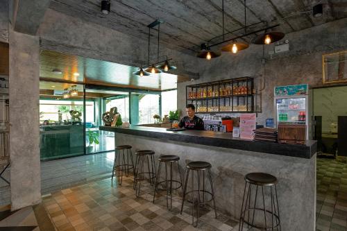 a woman sitting at a bar in a restaurant at The Bell Airport Phuket Hotel - SHA Extra Plus in Nai Yang Beach