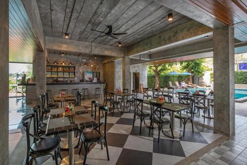 a restaurant with tables and chairs and a swimming pool at The Bell Airport Phuket Hotel - SHA Extra Plus in Nai Yang Beach