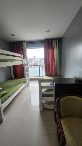 a room with two bunk beds and a chair and a window at Conifer Baguio in Baguio