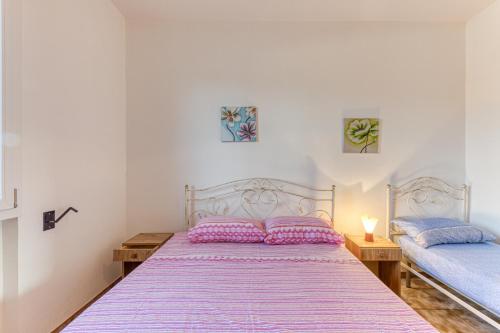 een slaapkamer met 2 bedden met roze en blauwe kussens bij Casa Sofia in Torre Pali 