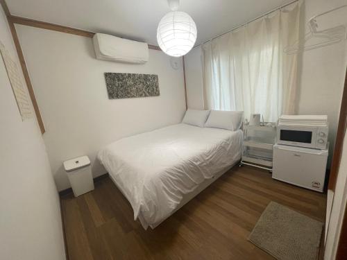 a small bedroom with a white bed and a microwave at Hostel JL in Chung-jeong in Seoul