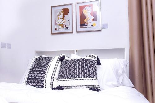 a bed with black and white pillows and framed pictures at AZURE - the perfect escape in Tema