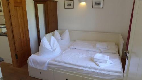 a bed with white sheets and pillows on it at Gut-Rattelvitz-Parterre-C-hochwertig-Sauna-Kamin-eTankstelle-Spielscheune-15-000qm-Parkland in Gingst
