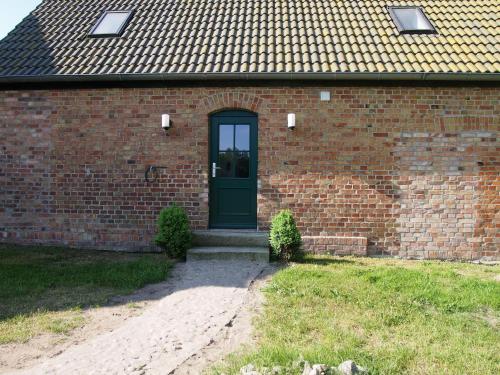 a brick building with a green door on it at Gut-Rattelvitz-Parterre-C-hochwertig-Sauna-Kamin-eTankstelle-Spielscheune-15-000qm-Parkland in Gingst