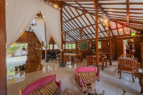 a pavilion with tables and chairs and a pool at Omah Gili Hotel in Gili Air