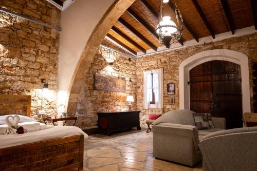 a room with a stone wall with a bed and a couch at Oinoessa Traditional Boutique Guest Houses in Lofou