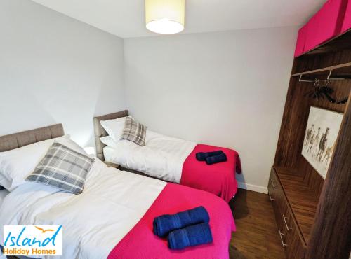 twee bedden in een slaapkamer met roze en wit bij Folly View in Newport