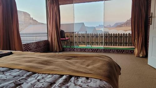 een slaapkamer met een bed en een groot raam bij Rum Grand Tours Camp in Disah