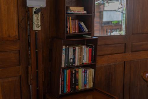 a book shelf filled with books next to a window at Omah Gili Hotel in Gili Air