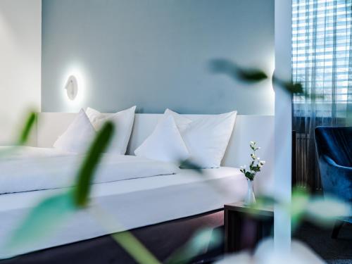 un letto bianco con cuscini bianchi in una stanza di Hotel Royal a Stoccarda
