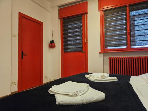 una camera da letto con porte rosse e asciugamani bianchi su un letto di Red Velvet Residence a Bucarest